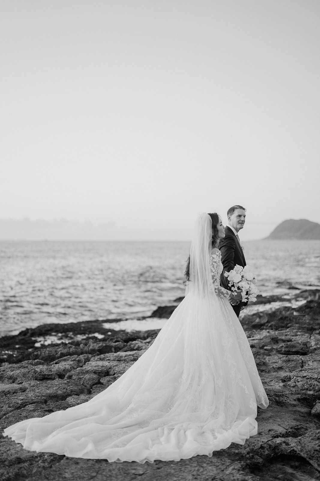 black and white photo of bride and groom on rocks